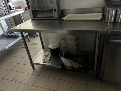 a stainless steel table in a kitchen with a microwave and dishwasher