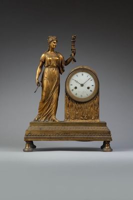 a statue of a woman holding a clock on a table