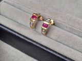une paire de boucles d'oreilles en rubis et diamants, dans un écrin posé sur une table