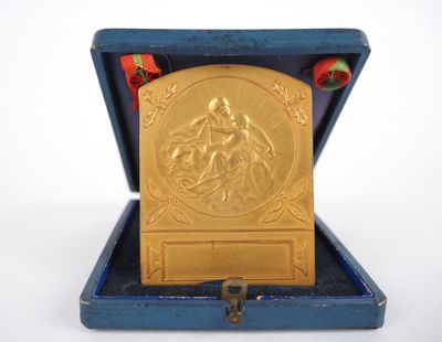 une médaille d'or dans une boîte bleue posée sur une surface blanche