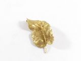 broche en feuille d'or sertie de diamants sur fond blanc