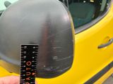 a person holding a measuring tape in front of a yellow car