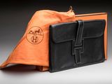 an orange and black bag sitting on top of a table next to a brown bag