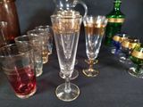 many glasses and a pitcher sitting on a table