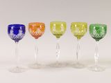 four different colored wine glasses are lined up on a white surface