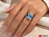 an image of a woman ' s hand with a blue topaz ring