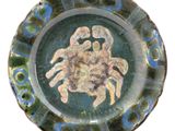 une assiette bleue et verte sur laquelle est représenté un crabe