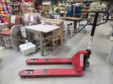 un chariot élévateur rouge dans un entrepôt rempli de meubles
