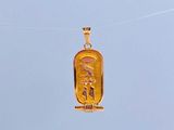 a gold pendant with an egyptian design hanging from a rope