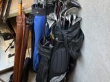 Plusieurs clubs de golf sont alignés contre un mur dans un garage