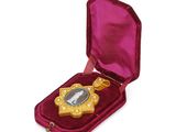 an image of a gold medal in a velvet case on a white background