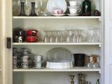 Il y a beaucoup de vaisselle et de verres sur les étagères de cette cuisine