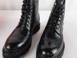 des bottes en cuir noir à semelles noires posées sur une surface blanche
