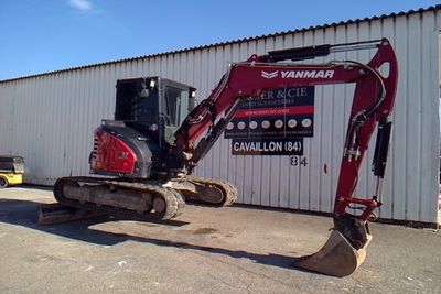 a small red excavator parked in front of a building