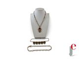 a necklace, bracelet, and ring on display on a mannequin
