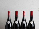 quatre bouteilles de vin rouge alignées sur une table en bois