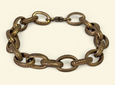 une photo en gros plan d'un bracelet à maillons posé sur une surface blanche