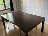 une table et des chaises en bois dans une pièce avec du papier peint
