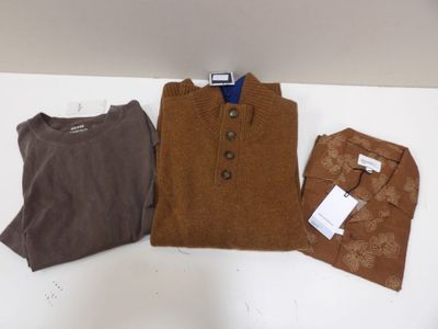 Trois pulls pour homme, dont un marron et un autre marron, sont posés sur une table blanche