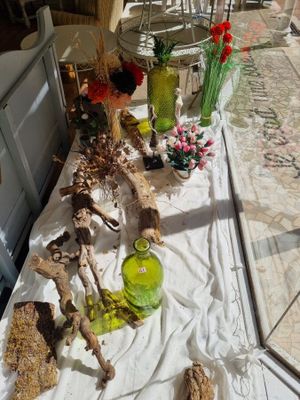 une longue table sur laquelle sont disposés plusieurs vases et des fleurs