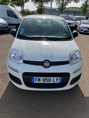La petite voiture blanche est garée sur le parking, à côté d'autres voitures.