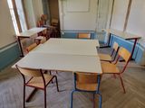 des tables et des chaises dans une salle de classe vide, avec un tableau blanc accroché au mur