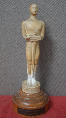une image représentant une statue d'un homme debout sur un socle en bois