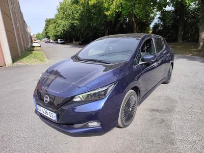 the blue nissan leaf is parked on the side of the road