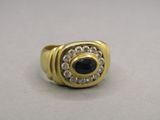 an image of a gold ring with a black stone surrounded by white diamonds