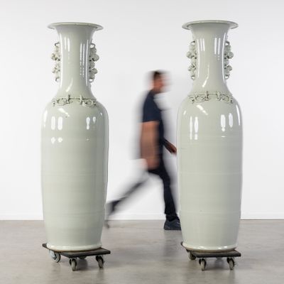 deux grands vases blancs posés sur des roulettes dans une pièce