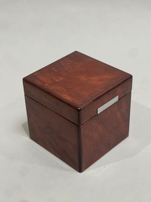 boîte en bois marron avec un couvercle argenté, posée sur un fond blanc