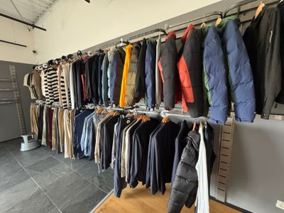 beaucoup de vêtements suspendus à une étagère dans une pièce