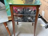 a small table with a glass top and a drawer with a cat on it