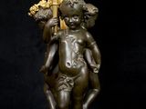 a bronze statue of a child holding a candelabra