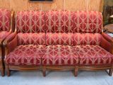 un canapé rouge et deux fauteuils dans une pièce