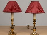 une paire de lampes rouges posées sur une table en bois, avec un mur blanc en arrière-plan