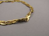 gros plan d'un bracelet en or sur une surface grise