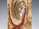 sculpture of a red starfish in a stone block on a white surface