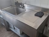 un évier en acier inoxydable dans une cuisine, à côté d'un radiateur