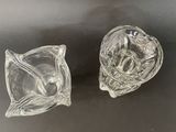 pair of clear glass ashtrays on a black surface