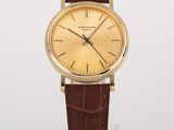 a close up of a gold watch with a brown leather strap