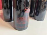 three bottles of red wine are lined up on a table