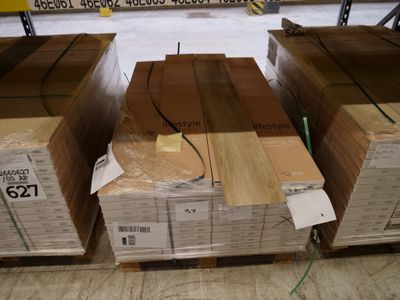 Plusieurs caisses en bois sont empilées sur des palettes dans un entrepôt