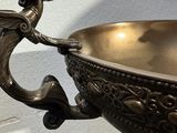 a metal bowl with a bird on it on a table