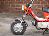a small red motorcycle parked in front of a brick wall