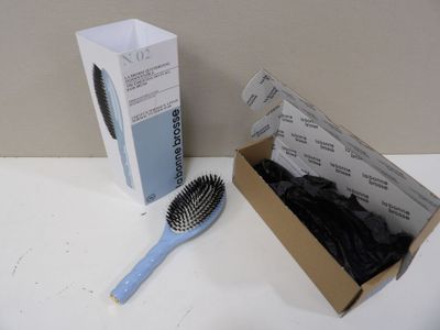 une boîte de brosses à cheveux et une brosse posées sur une table