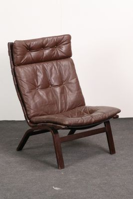the chair is made of brown leather and has a wooden frame