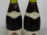 two bottles of red wine sitting next to each other on a table