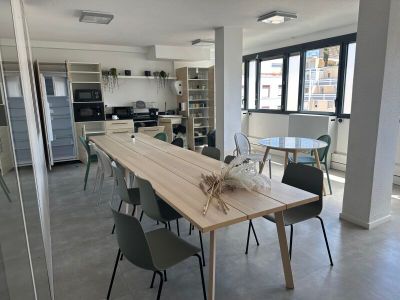 une longue table avec des chaises et un vase posé dessus, au milieu d'une pièce