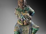 a statue of a man sitting on a chair with a bird in his hand